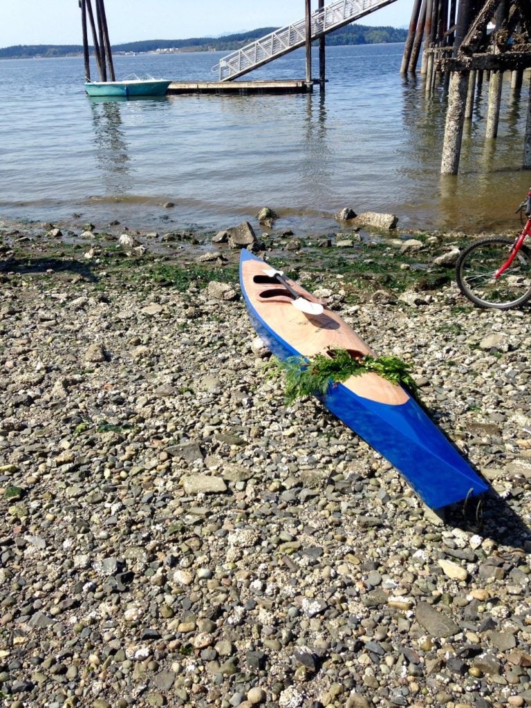 wood and blue kayak on rocks near Puget Sound