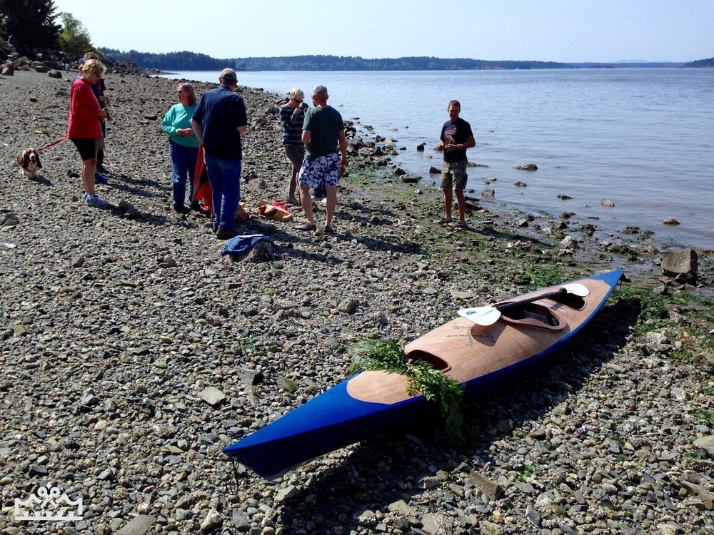group of people standing on shore of Puget Sound looking at kayak