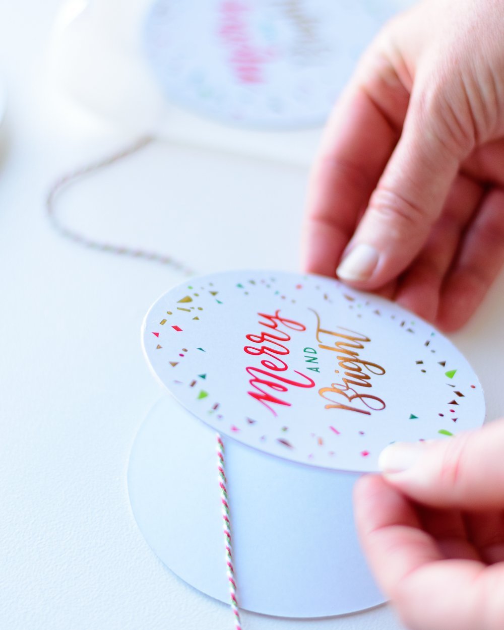 woman gluing paper coaster to string 