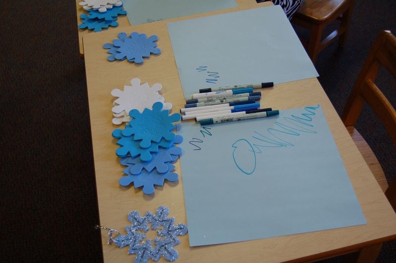 foam snowflakes on table with paper and markers