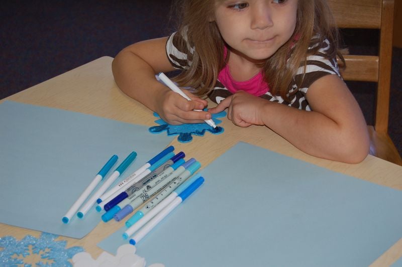 little girl at table coloring snowflake 