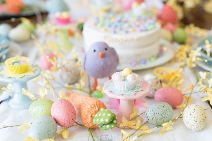 purple bird, Easter eggs, and white cake on bright spring Easter table