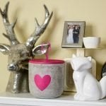 A mantel with a silver deer head and a candle with a heart painted on it