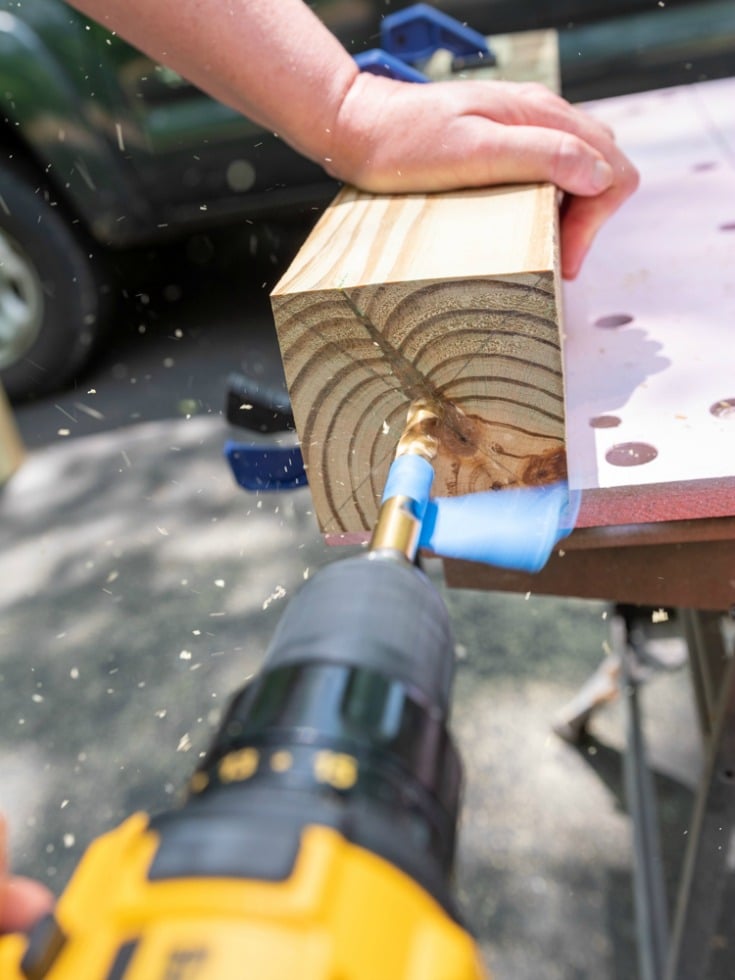 woman drilling hole into wood lumber