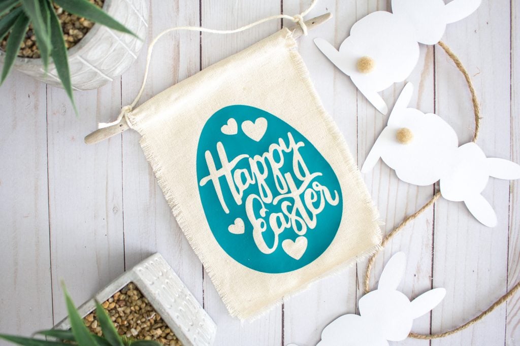 fabric Happy Easter egg banner laying on table next to plants