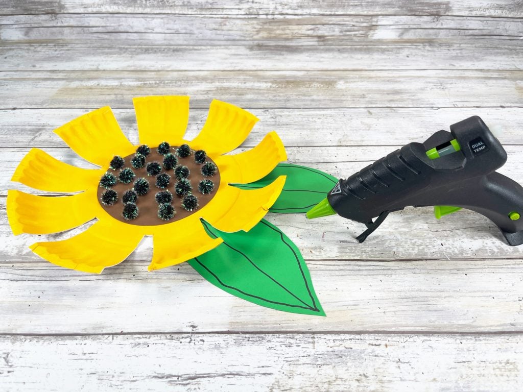 gluing leaves onto paper plate sunflower