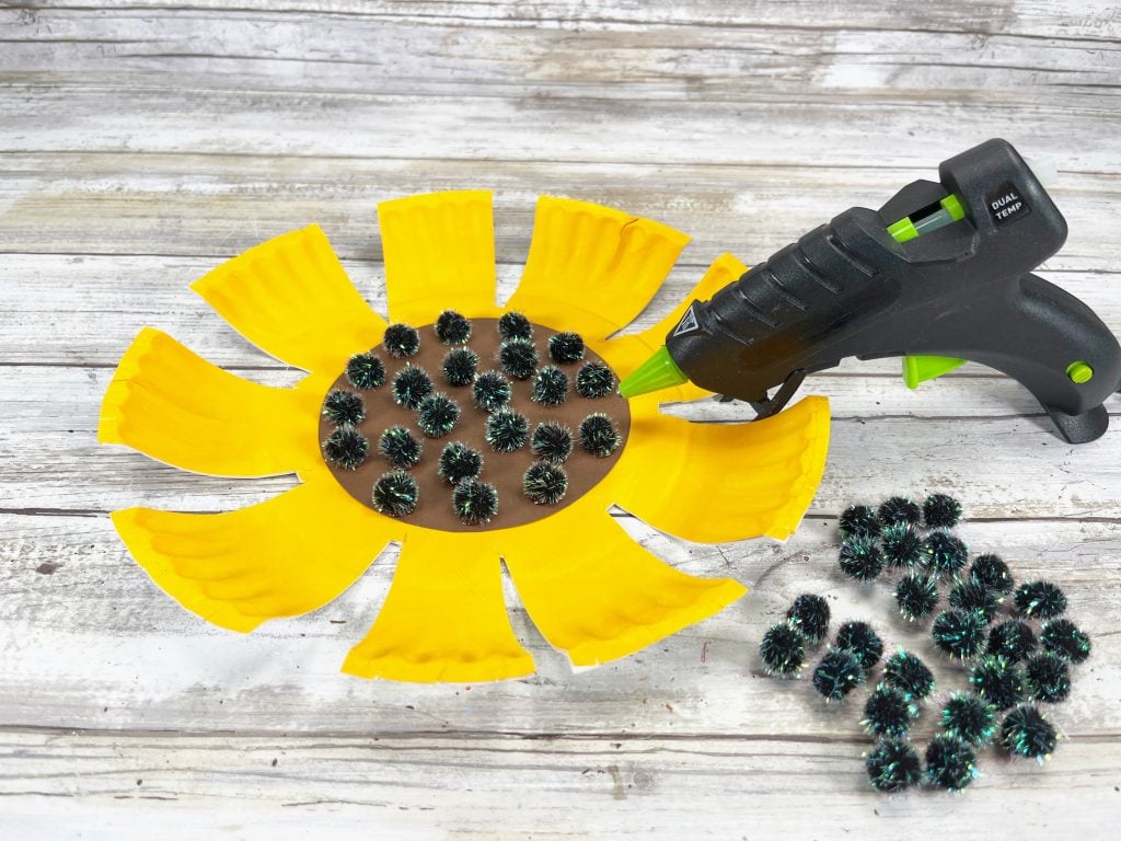 gluing black pom poms to center of sunflower